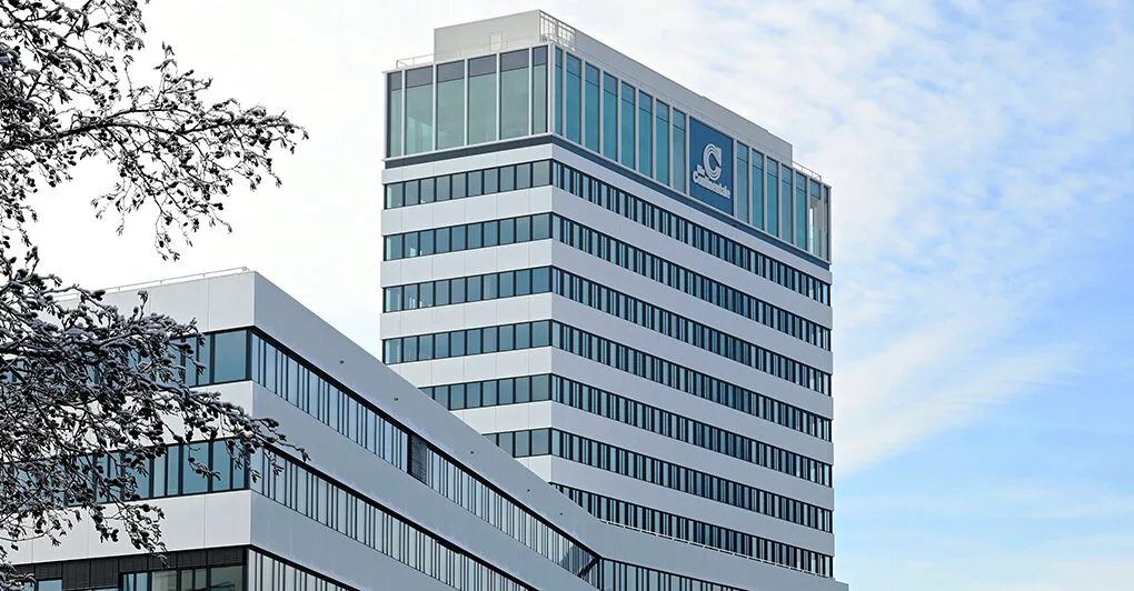 Continentale Campus Dortmund im Winter, weißes Bürohochhaus mit Fensterbändern hinter verschneiten Zweigen