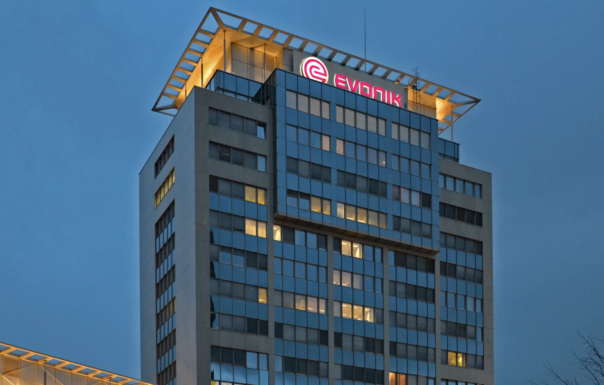 Evonik Hochhaus in der Abenddämmerung, Glasfassade mit beleuchteten Büros und Schriftzug auf dem Dach