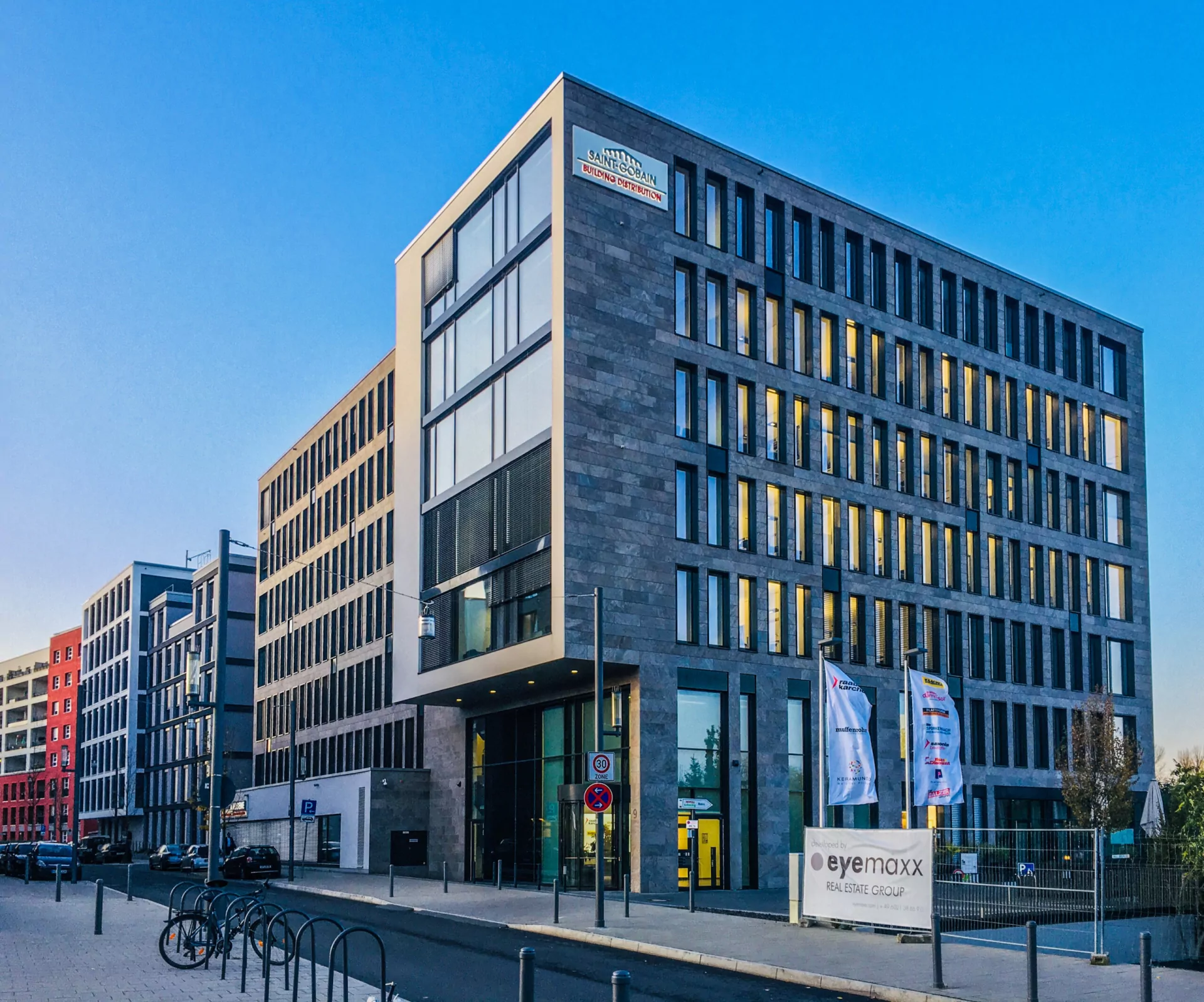 Saint-Gobain Bürogebäude mit dunkler Natursteinfassade und schmalen Fensterreihen an einer Straßenecke