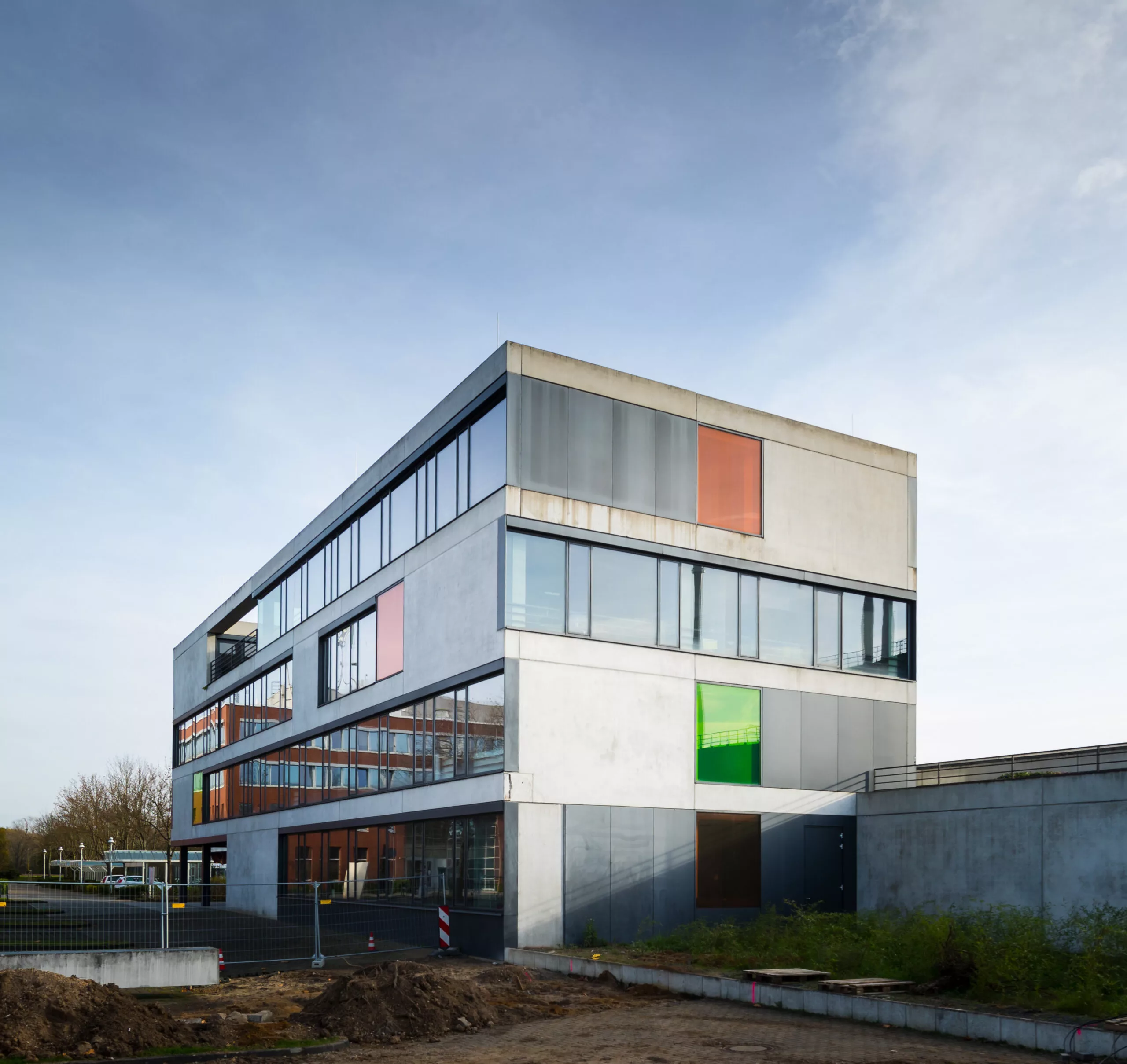 StEB Hauptverwaltung Köln-Merheim: Bürogebäude mit Betonfassade, farbigen Glasfeldern und Fensterbändern.